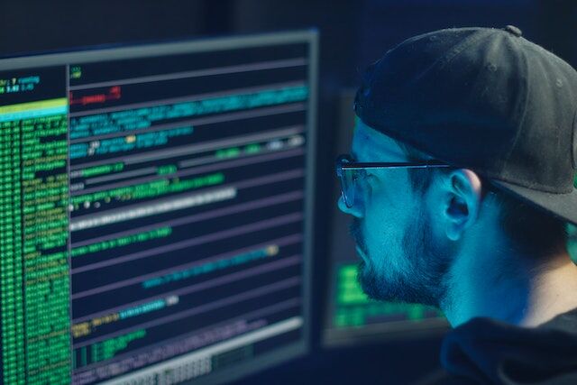 pexels-mikhail-nilov-6963098 | Path Social رجل ينظر إلى كود المطور على شاشة الكمبيوتر ليلاً.