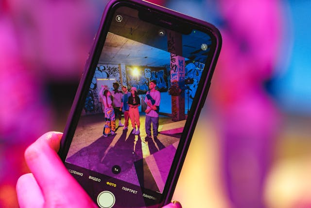 pexels-anthonyshkraba-production-8973459 | Path Social Qualcuno che tiene in mano un telefono per scattare una foto di un gruppo di amici in un luogo con graffiti sui muri per la propria IG Story.