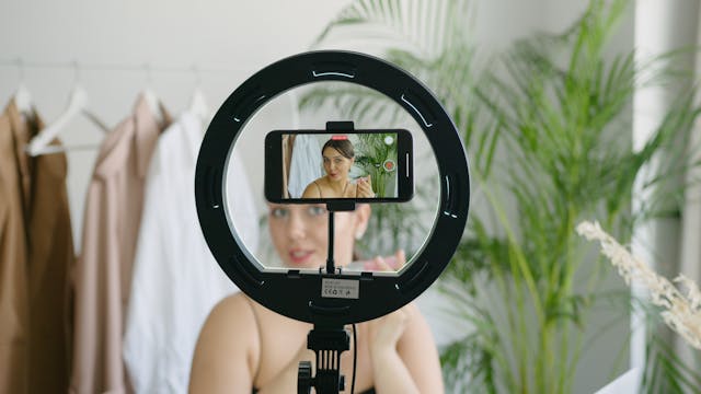 pexels-anna-nekrashevich-12432832 | Path Social A female content creator holding a beauty product recording a video of herself with a phone camera and ring light.