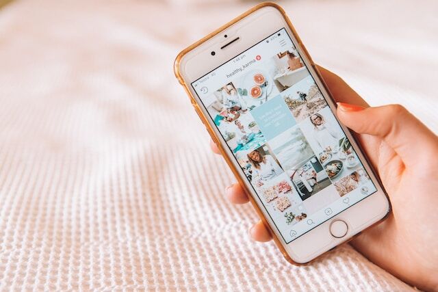 A person holding an iPhone displaying social media posts.