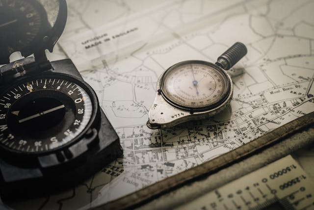 Shallow focus photograph of black and silver compasses on top of a map.
