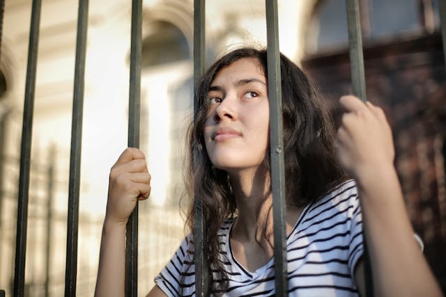 Woman staring through bars.
