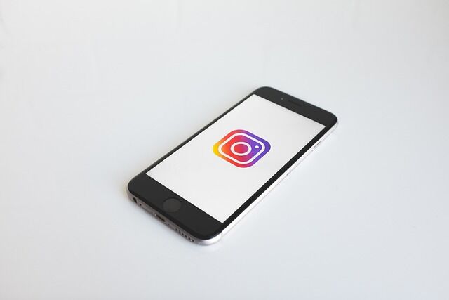 Zwarte smartphone met Instagram logo op witte achtergrond.
