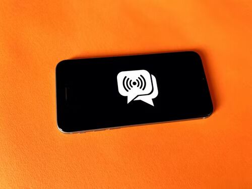 Un téléphone noir affichant deux icônes de chat de messages Instagram se chevauchant sur l'écran.