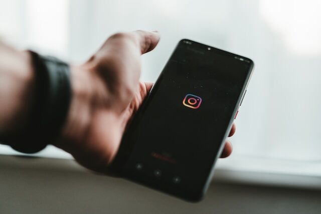 Uma imagem de uma pessoa segurando um telemóvel com o logótipo Instagram .