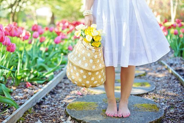 튤립 정원에서 노란 꽃바구니를 들고 있는 흰 드레스 차림의 여성.