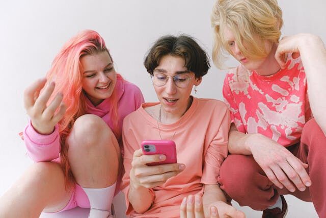 A group of people in pink looking at a smartphone. 